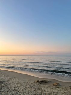 the sun is setting at the beach with waves in the water and sand on the shore