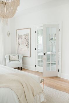 a bedroom with white walls and wood flooring has a chair in the foreground