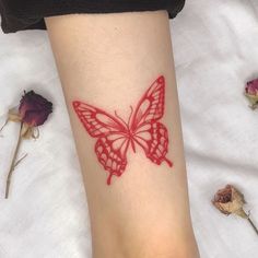 a woman's foot with a red butterfly tattoo on it