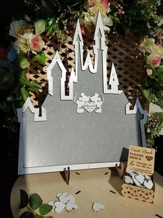 a castle made out of paper sitting on top of a table next to some flowers