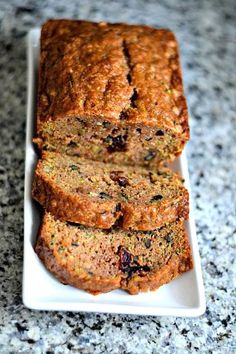 sliced loaf of fruity banana bread on a white plate sitting on a granite countertop