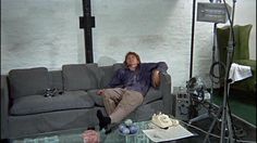 a man laying on top of a couch in a living room next to a table