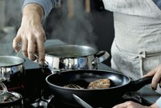 two people cooking food on top of a stove with pots and pans next to them