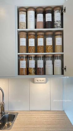 an open cabinet above a kitchen sink filled with spices