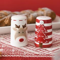 two salt and pepper shakers decorated with reindeer faces on them next to a plate of cookies