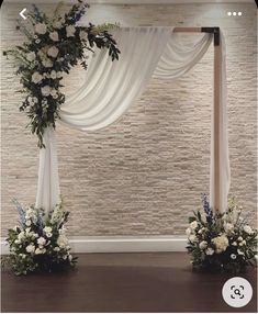 the wedding arch is decorated with white flowers and greenery for an elegant touch to the ceremony