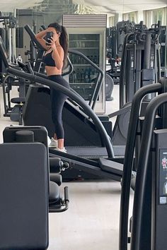 a woman is standing on a treadmill in the middle of a gym with other machines