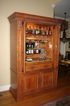 an old fashioned bar with liquor bottles on the top and bottom shelves, in a living room