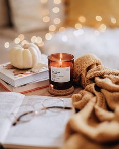 a candle sitting on top of an open book next to a pair of eyeglasses