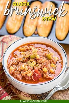 a close up of a bowl of soup with bread in the background