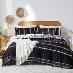 a bed with black and white bedspread, pillows and blankets on top of it