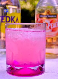 a pink drink sitting on top of a table next to bottles