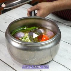 a person is cooking vegetables in a pot on a table with a video player nearby