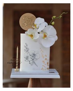 there is a white cake with flowers on it and a pen in front of it