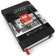 an open black book with a red ribbon around the cover and words on it that read arteza