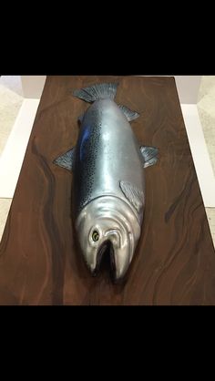 a metal fish sculpture sitting on top of a wooden table