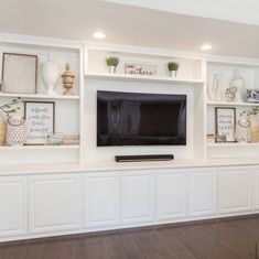 a living room with white built in shelves and a flat screen tv mounted on the wall