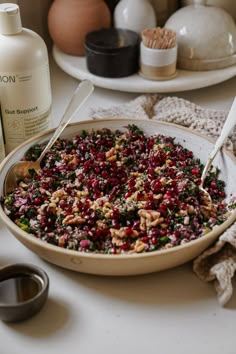 a bowl full of food sitting on top of a table next to bottles and spoons