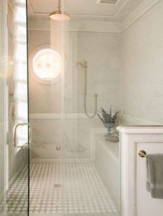 a bathroom with a glass shower door and white tile flooring, along with a bathtub in the corner