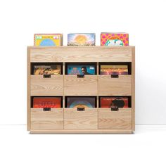 a wooden book shelf filled with books on top of each other and lots of bins