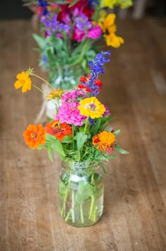 three vases filled with colorful flowers on top of a wooden table next to each other