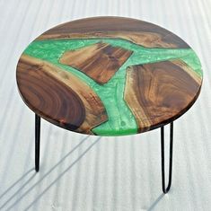 a wooden table with metal legs and green paint on the top, sitting in white sand