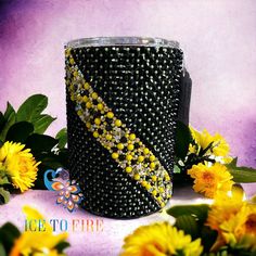 a black and yellow beaded cup with flowers around it