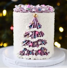 a white cake with purple icing and a christmas tree decoration on it's side