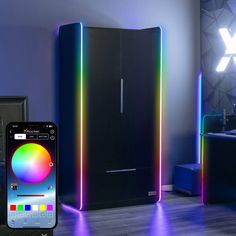 a cell phone sitting next to a black cabinet with rainbow lights on it and a tv in the background