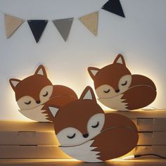 two paper fox lamps sitting on top of a wooden bench next to bunting flags