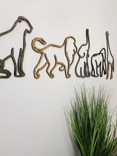 three metal dogs on a wall next to a potted plant