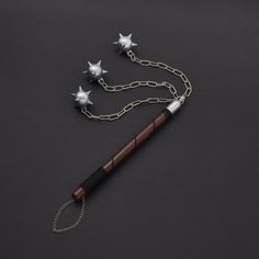 a pen with three stars attached to it on a black surface next to a chain