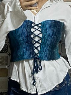 a close up of a person wearing a white shirt and blue knitted corset