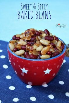 a red bowl filled with baked beans on top of a blue and white table cloth