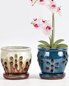 two vases with flowers in them sitting next to each other on a white surface