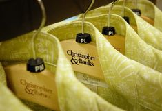 clothes hanging on wooden hangers with name tags attached to them in a store display