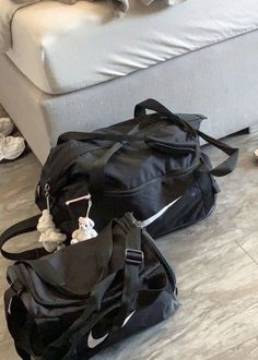 two duffel bags sitting on the floor next to a couch