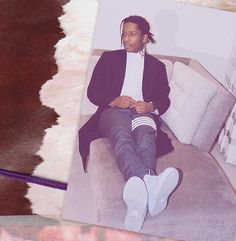 a man sitting on top of a couch next to a cowhide rug and a photo of him