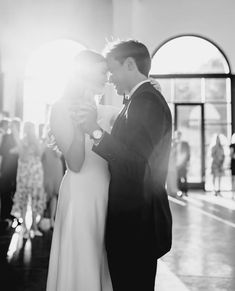 a bride and groom sharing a first dance at their wedding in black and white photo