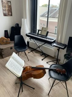 a violin and music equipment are sitting on the floor in front of an open window