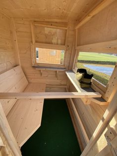 the inside of a small wooden cabin with green grass and water in the window sill