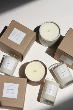 six candles sitting on top of a table next to some brown boxes with white labels