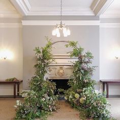 the room is decorated with white flowers and greenery on either side of the fireplace