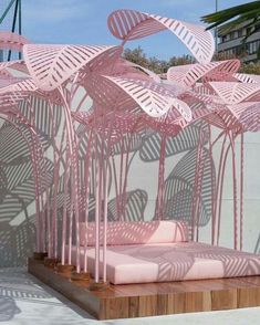 a pink couch sitting in front of a wall with umbrellas on top of it