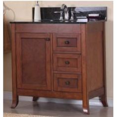 a bathroom vanity with black marble top and dark wood cabinetry, along with a rug on the floor