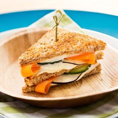 a sandwich with cheese, cucumber and carrots on a paper plate