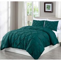 a bed with green comforter and pillows in a room