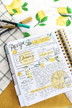 a recipe book with lemons on it next to markers and pens, along with other kitchen utensils