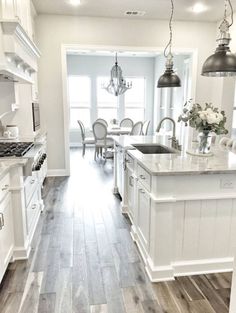 a large kitchen with white cabinets and wood flooring is seen in this image from the front door