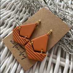 an orange pair of earrings sitting on top of a piece of paper